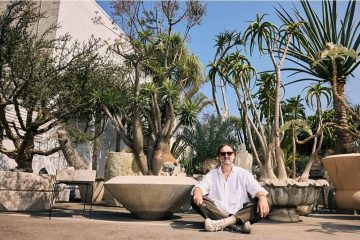 Eric Wareheim surrounded by a collection of unusual and rare plants in an artistic indoor setting.