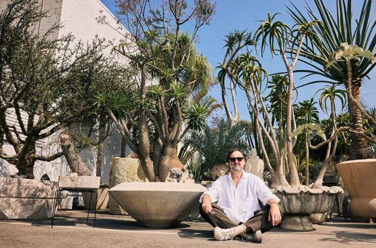 Eric Wareheim surrounded by a collection of unusual and rare plants in an artistic indoor setting.