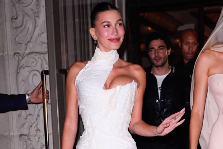 Hailey Bieber wears a sheer creamy nude manicure with a glossy finish in the sweet cream nail trend.