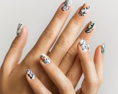 A minimalist animal-print manicure featuring subtle leopard, zebra, crocodile, and cow-inspired nail designs.