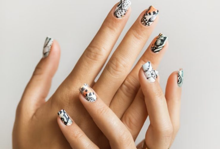 A minimalist animal-print manicure featuring subtle leopard, zebra, crocodile, and cow-inspired nail designs.