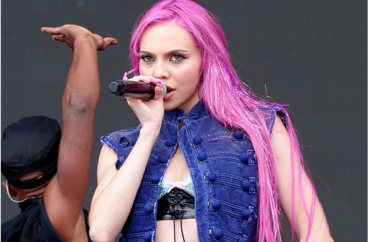 A woman with glossy pink hair in a soft rose shade showcasing the 2026 pink hair color trend.