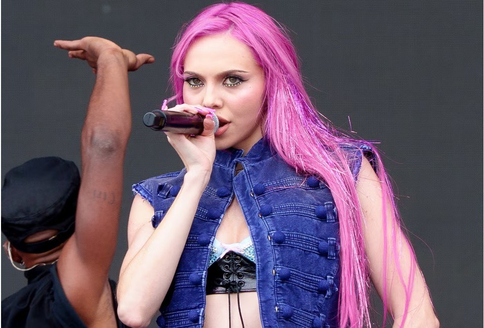 A woman with glossy pink hair in a soft rose shade showcasing the 2026 pink hair color trend.