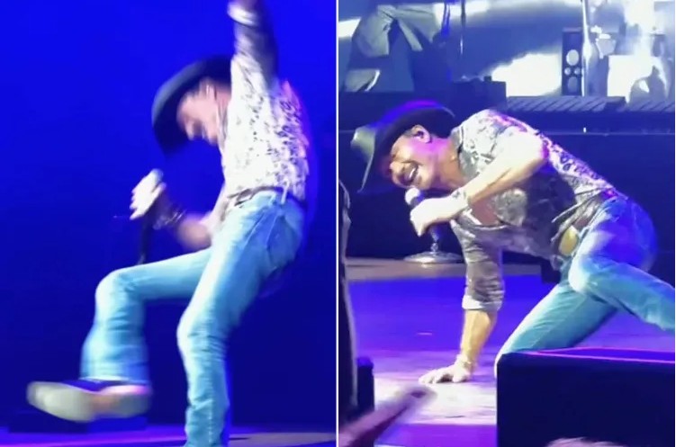 Tim McGraw performs onstage during his Cincinnati concert before falling after his cowboy boot catches on the stage floor.