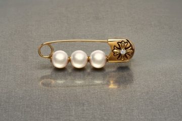 Pearl jewelry styled with gothic metal details, safety pins and layered chains for a modern punk-inspired look.