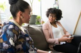 Mental health professional having a supportive conversation with a diverse client in a welcoming healthcare setting.