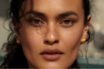 Five sheer bronzer products are displayed with makeup brushes to showcase lightweight formulas for creating a natural, dewy sun-kissed complexion.