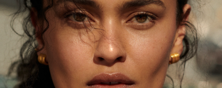 Five sheer bronzer products are displayed with makeup brushes to showcase lightweight formulas for creating a natural, dewy sun-kissed complexion.
