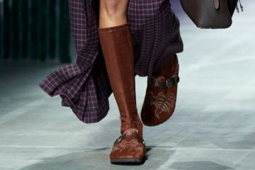A pair of Birkenstock by Etro shoes showcases suede, paisley-inspired detailing, fringe, and Western-style hardware against an earthy backdrop.