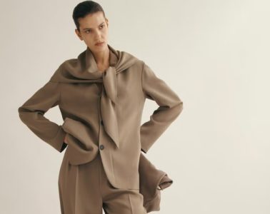 A model wears a polished brown tailored suit with a coordinating scarf, showcasing a sophisticated fall-ready office outfit with modern appeal.