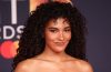 A woman with defined curly hair demonstrates a moisture-layering routine designed to enhance hydration, shine, softness, and natural curl definition.