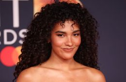 A woman with defined curly hair demonstrates a moisture-layering routine designed to enhance hydration, shine, softness, and natural curl definition.