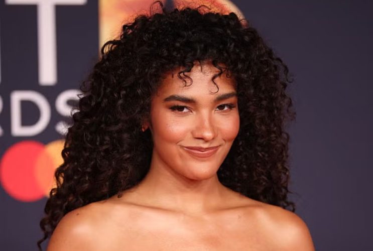 A woman with defined curly hair demonstrates a moisture-layering routine designed to enhance hydration, shine, softness, and natural curl definition.